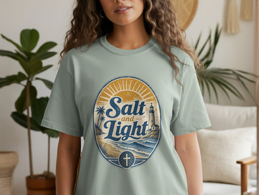 Light blue t-shirt with oval graphic: Salt and Light, lighthouse, beach, and cross.