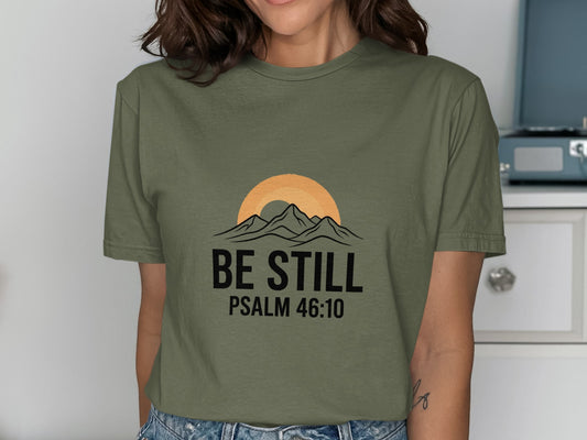 Olive green t-shirt with "BE STILL PSALM 46:10" and mountain sunset design.