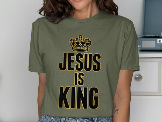 Olive green t-shirt with black text "JESUS IS KING" and gold crown.
