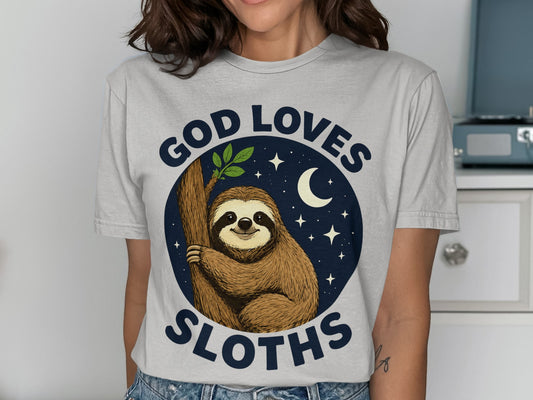 Sloth hanging on tree branch, moon and stars, "God Loves Sloths" text.