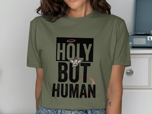 Olive t-shirt with "HOLY BUT HUMAN" text and small angel graphic.