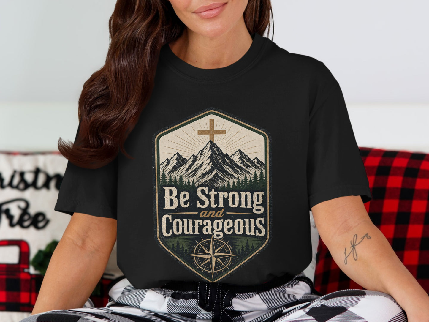 Black t-shirt graphic with mountains, cross, compass, and text "Be Strong and Courageous".