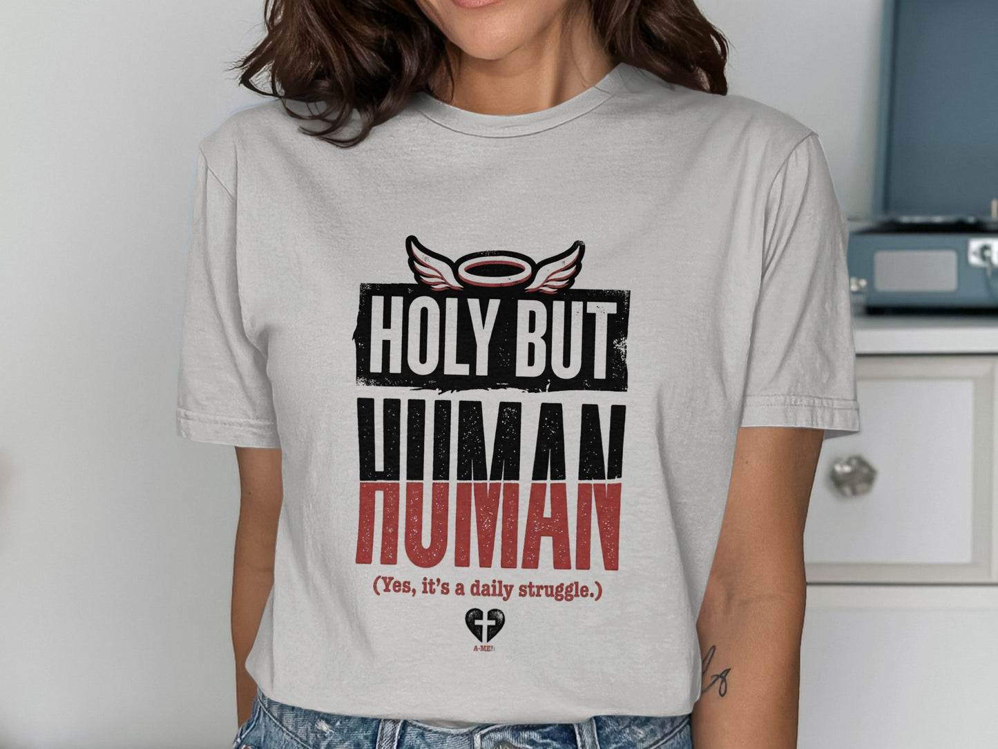 Grey t-shirt with "HOLY BUT HUMAN" and wings graphic.