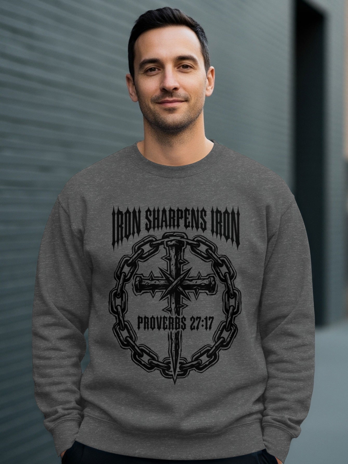 Man wearing a gray sweatshirt with "IRON SHARPENS IRON PROVERBS 27:17" and a cross design.