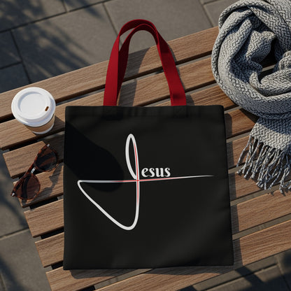 Black tote bag with white and red "Jesus" graphic and red handles.