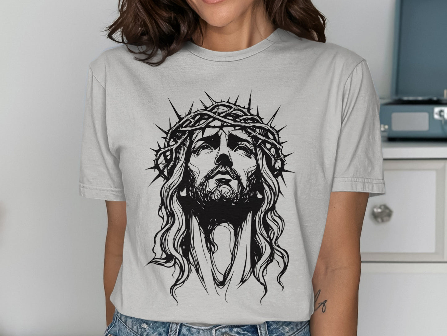 Black and white graphic of Jesus Christ with a crown of thorns on a gray t-shirt.