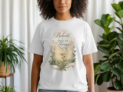 White t-shirt with "Behold, I Make All Things New" text and floral landscape art.