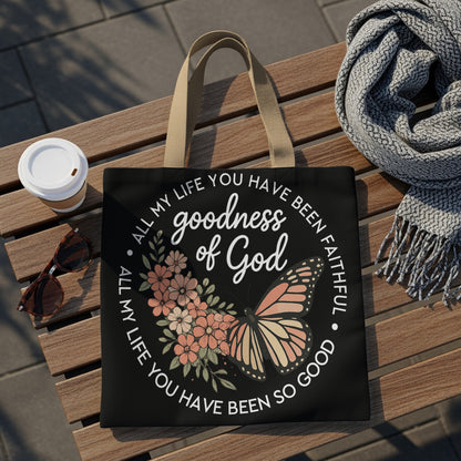 Black tote bag with "Goodness of God" text, floral design, and butterfly.