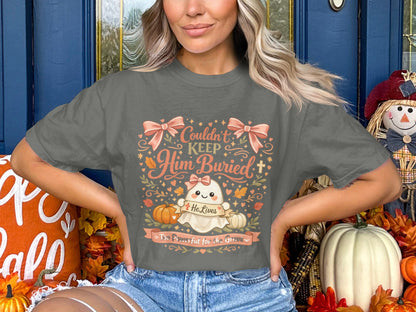 Ghost graphic on a t-shirt with text: Couldn't Keep Him Buried, He Lives, Too Powerful for the Grave.
