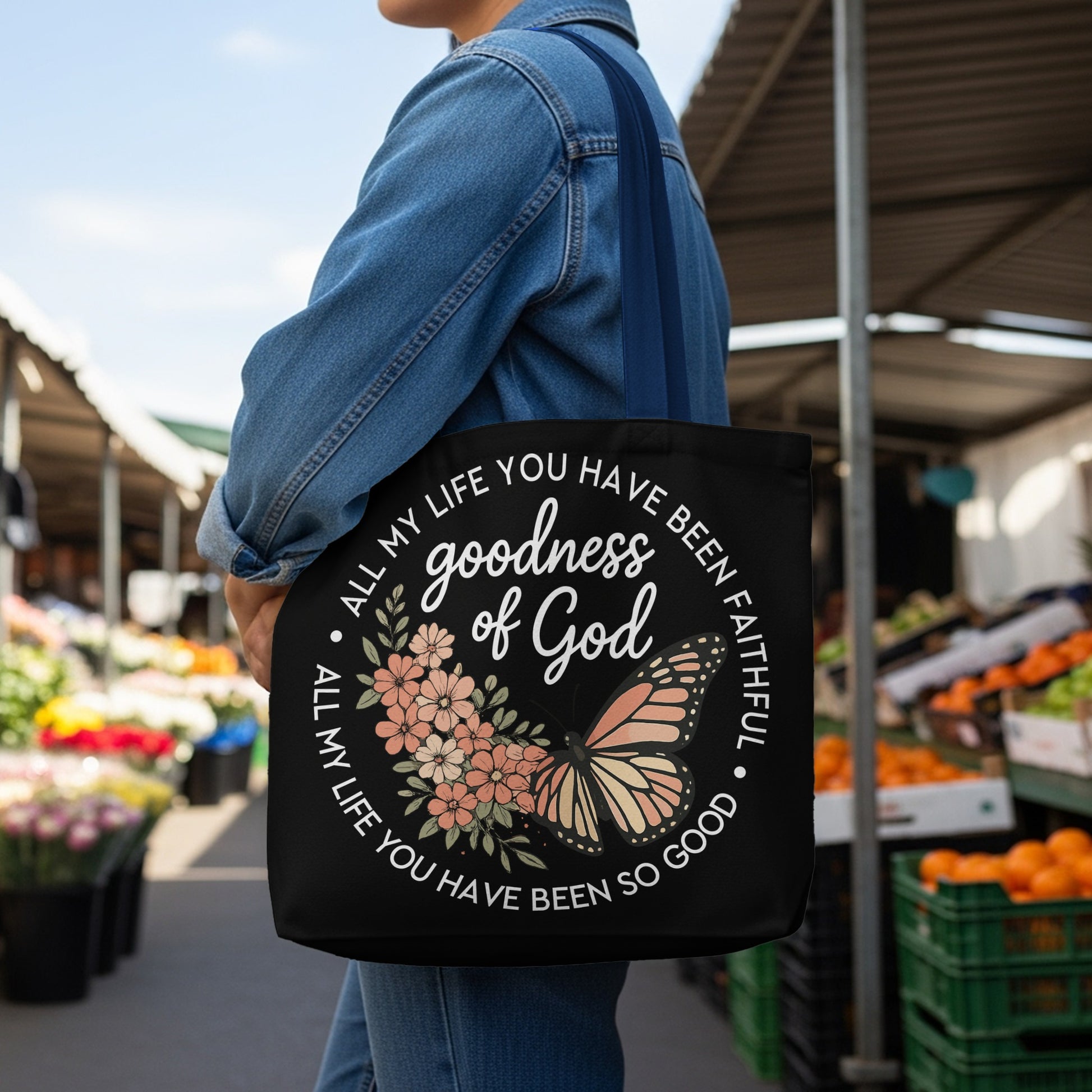 Black tote bag with "goodness of God" and floral butterfly design.