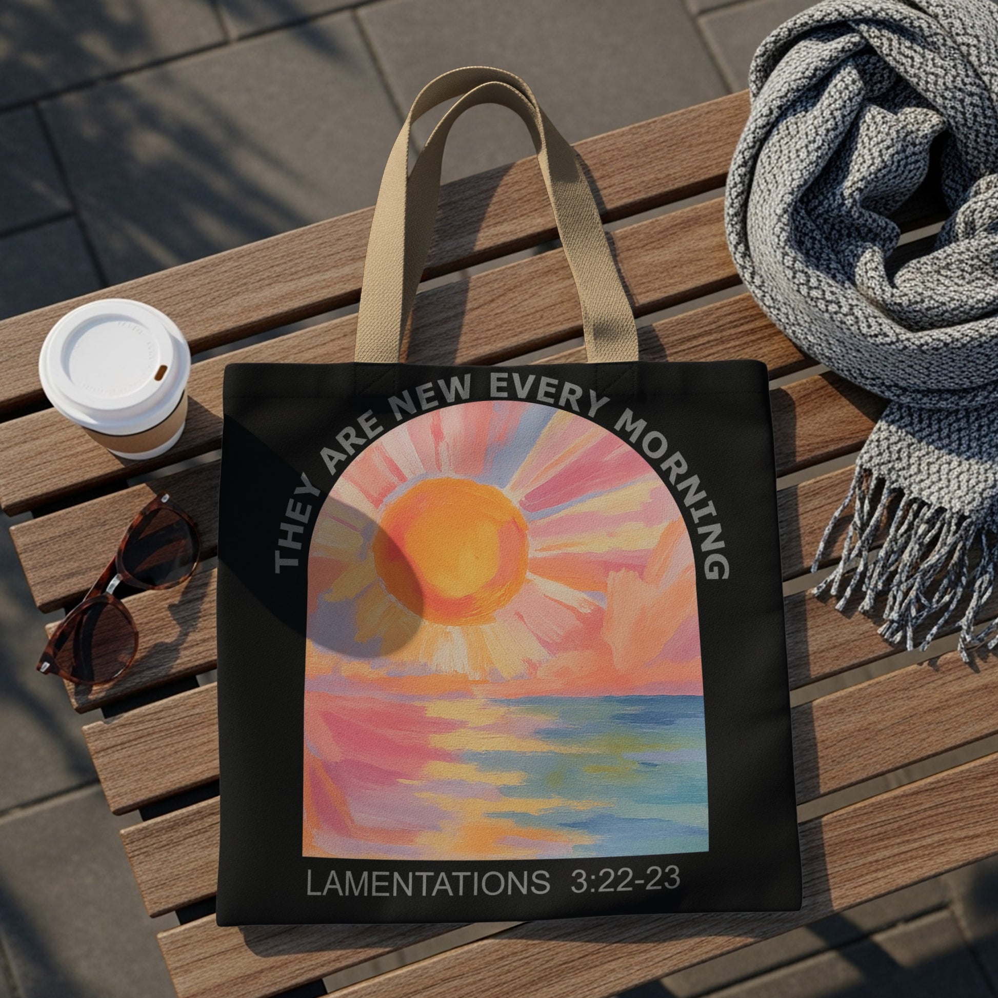 Black tote bag with painted sunrise over ocean and text: "They are new every morning"
