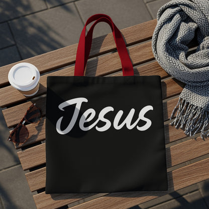 Black tote bag with red handles featuring white text that says "Jesus."