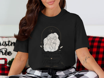 Black t-shirt with line art of a woman praying and text "She Believed She Could, So She Prayed".