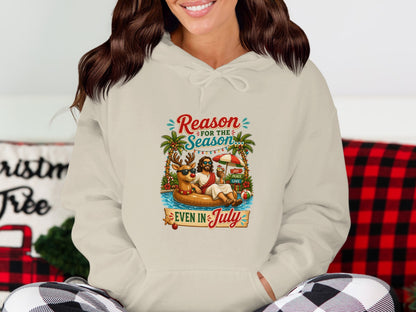 Cream hoodie with "Reason for the Season Even in July" graphic of a reindeer on an inflatable.