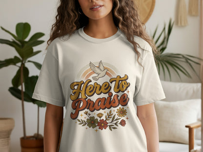 Cream t-shirt with retro "Here to Praise" text, dove, rainbow, and flowers graphic.