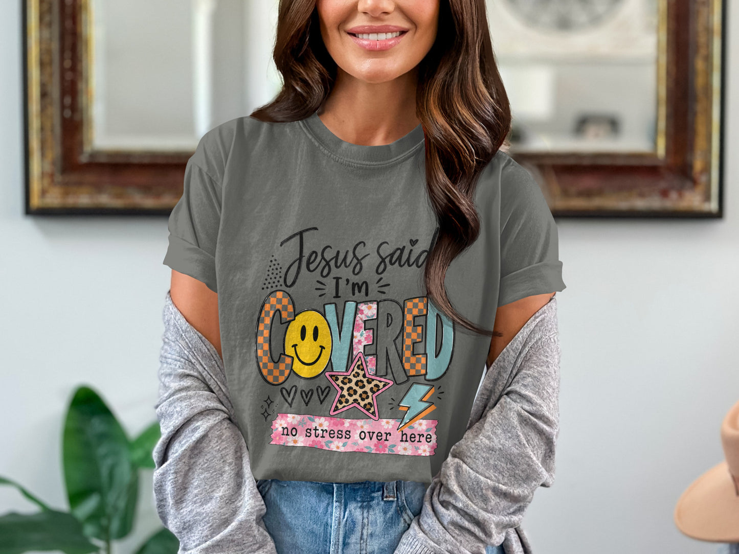 Graphic tee with "Jesus said I'm COVERED no stress over here" text and decorations.