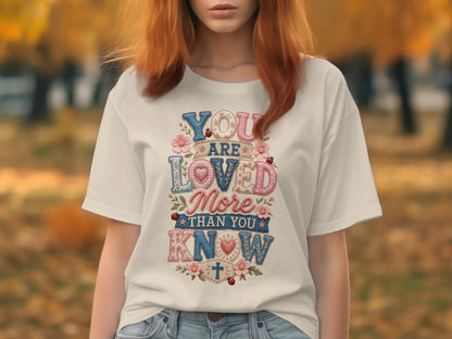 T-shirt with "YOU ARE LOVED MORE THAN YOU KNOW" text and floral, ladybug accents.