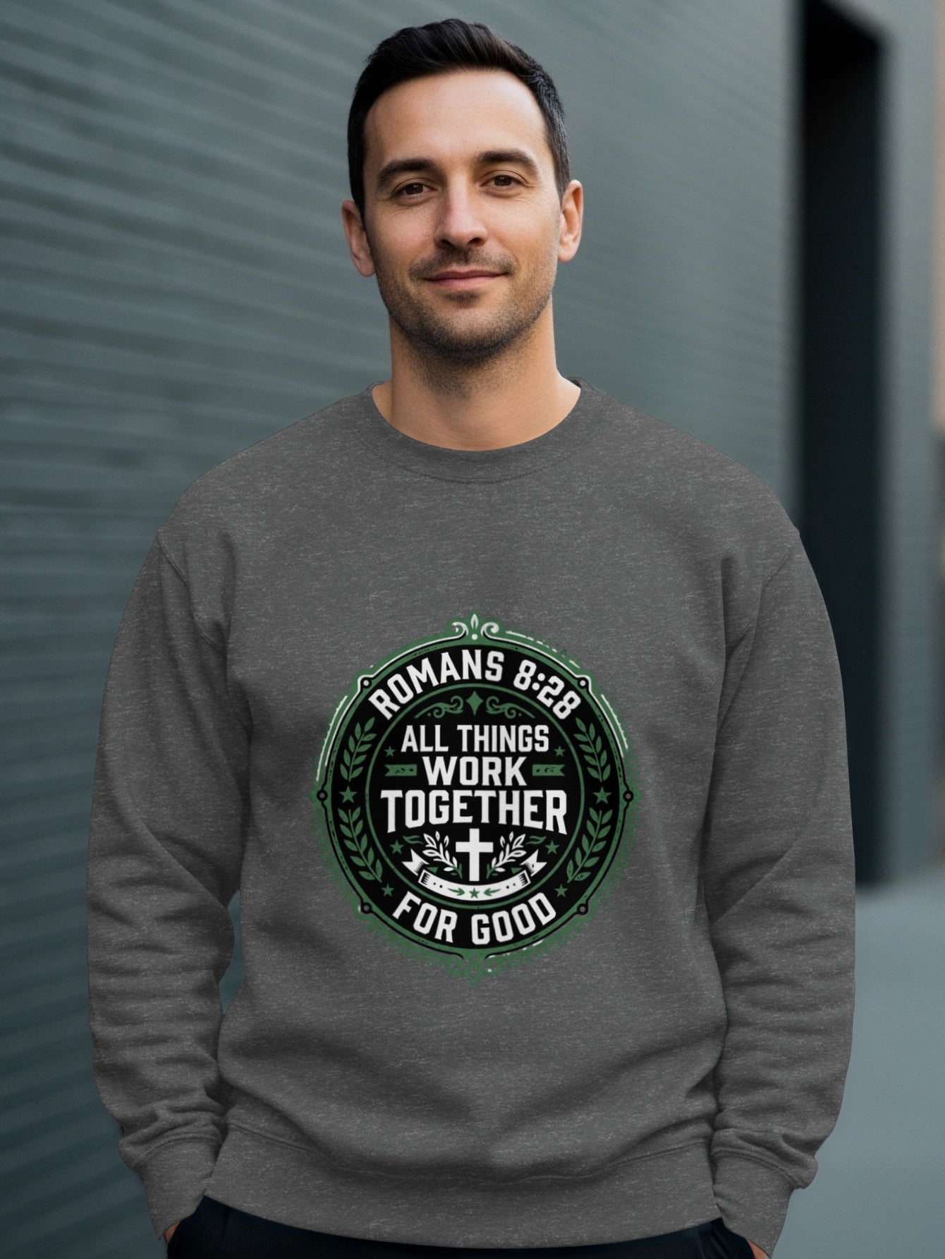 Man wearing dark grey sweatshirt with "Romans 8:28 All Things Work Together For Good" text.