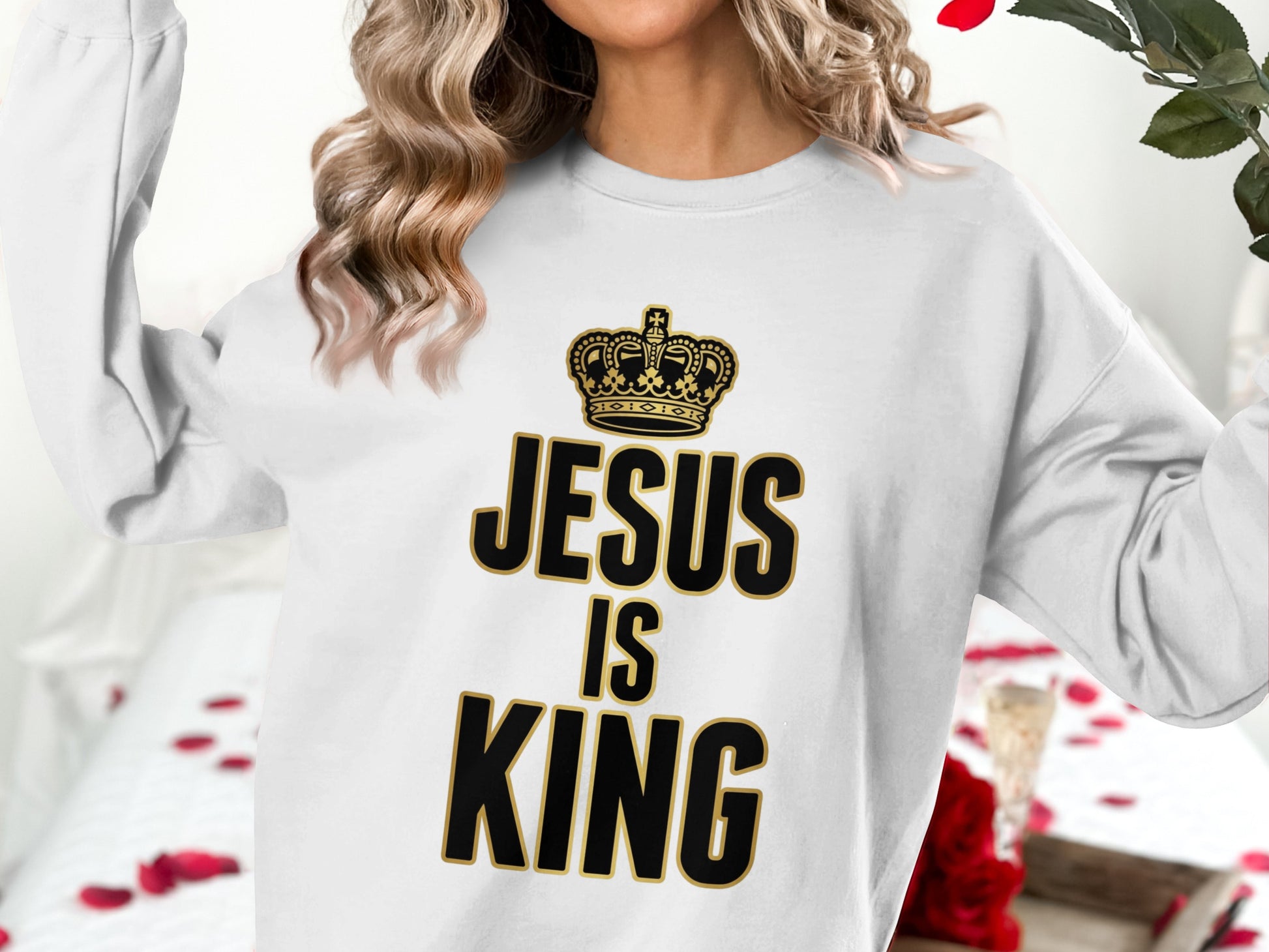 White sweatshirt with gold text "Jesus is King" and a crown graphic.