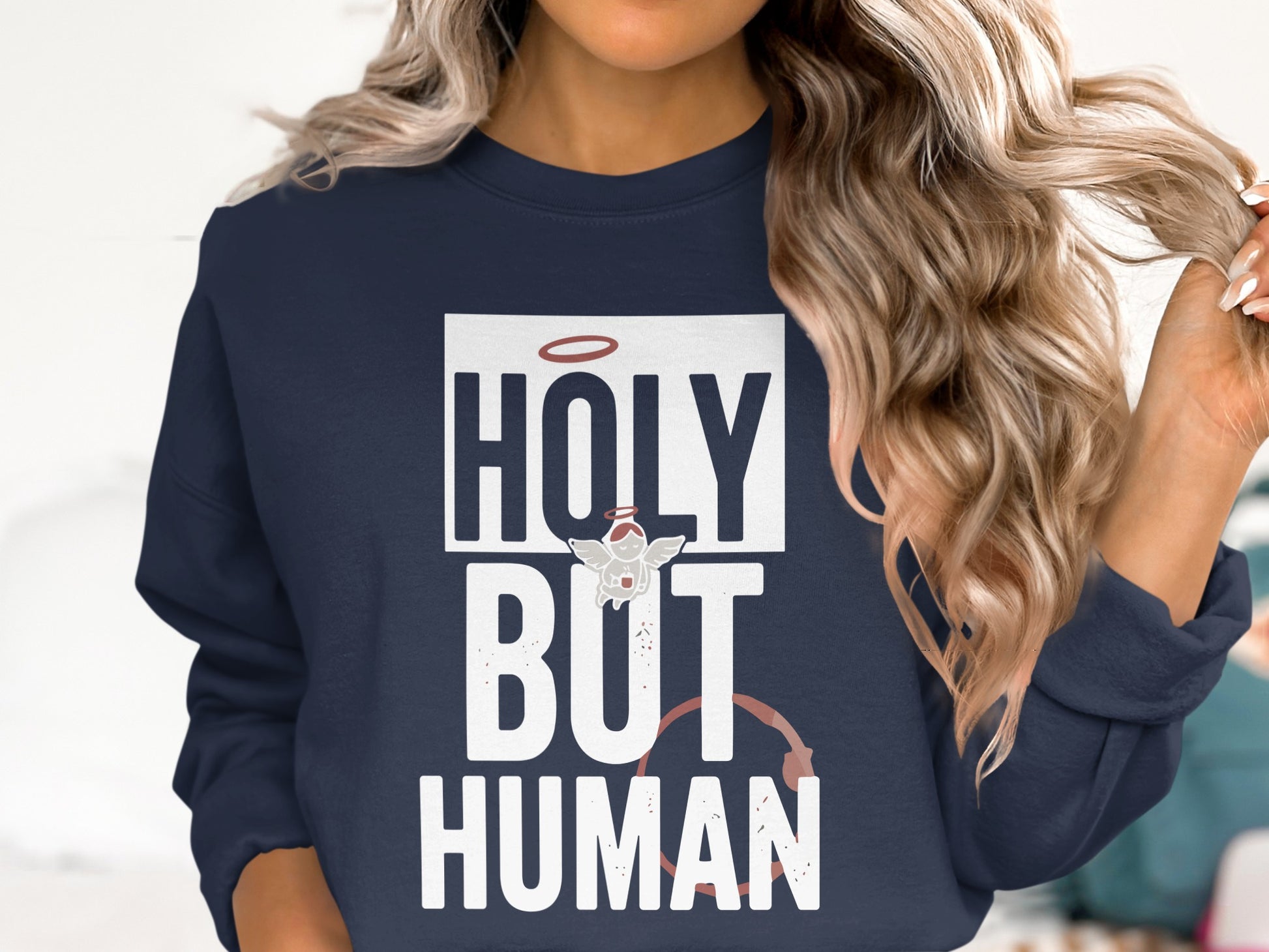 Navy sweatshirt with "HOLY BUT HUMAN" text and halo graphic.