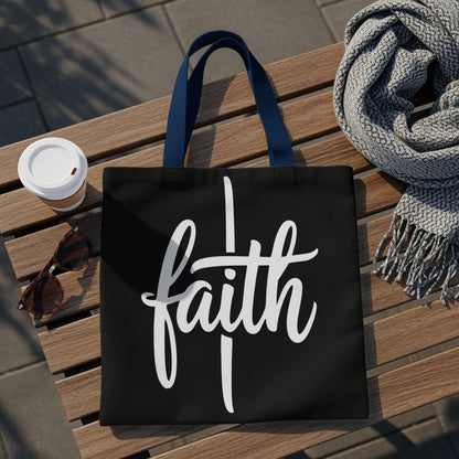 Black tote bag with "faith" in white script, on a wooden bench with a scarf and coffee cup.