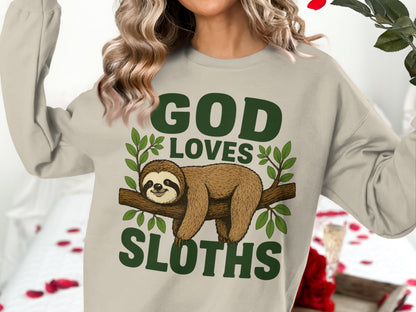 Woman wearing a tan sweatshirt with "God Loves Sloths" and a sloth on a branch.