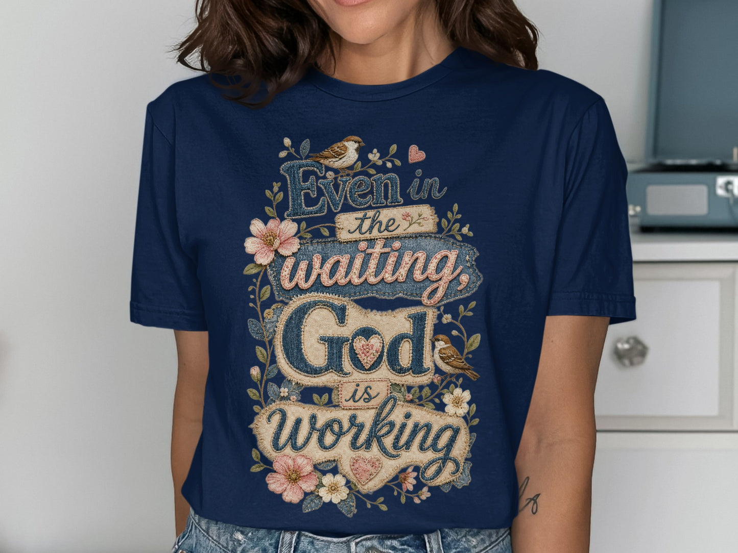 Navy t-shirt with "Even in the waiting God is working" text and floral accents.