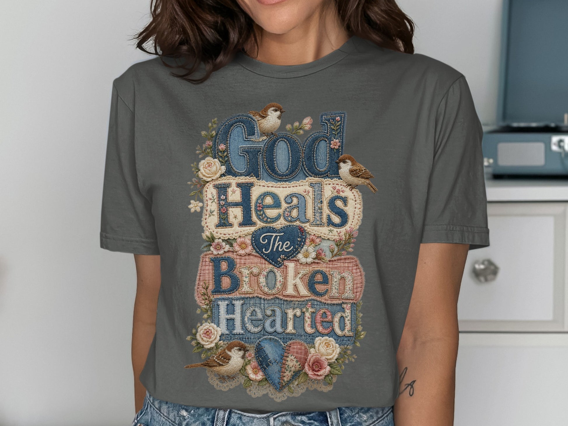 Dark gray t-shirt with "God Heals The Broken Hearted" text and floral embellishments.