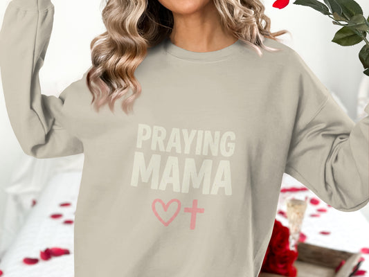 Light beige crewneck sweatshirt with "Praying Mama" and a heart with a cross.
