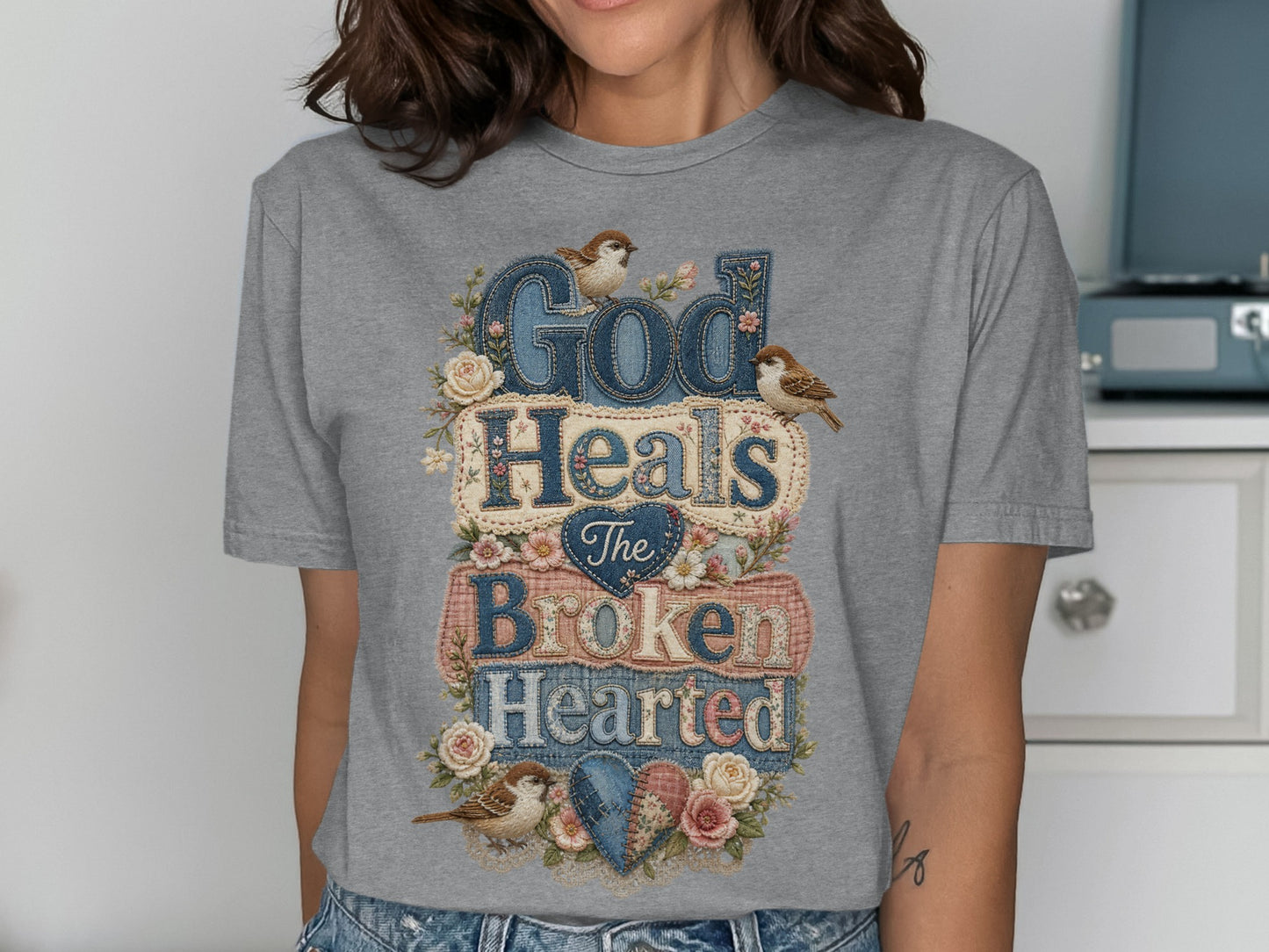 Gray t-shirt with "God Heals The Broken Hearted" text and floral accents.