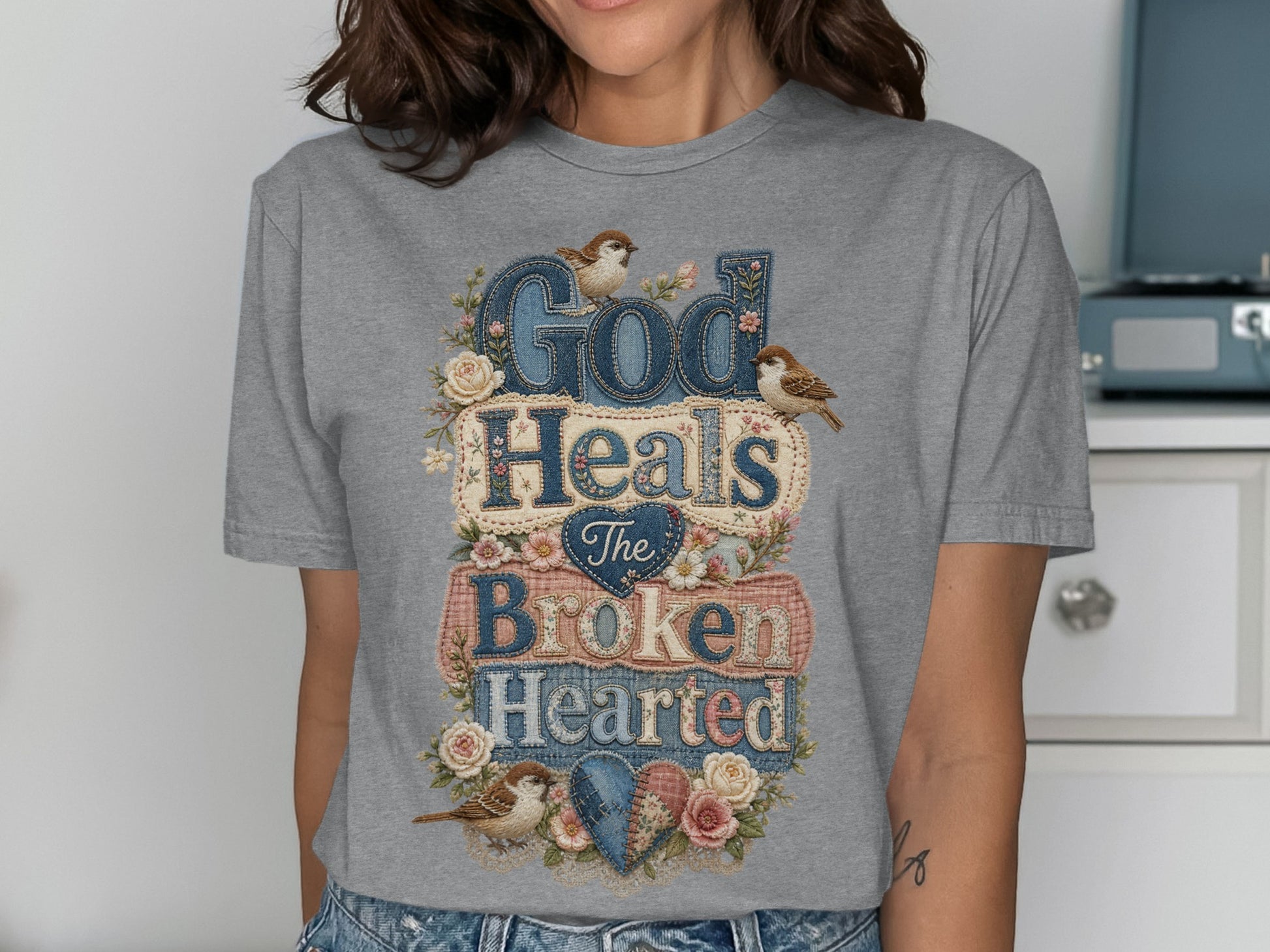 Gray t-shirt with "God Heals The Broken Hearted" text and floral accents.