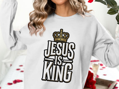 White sweatshirt with "Jesus is King" text and a gold crown graphic.