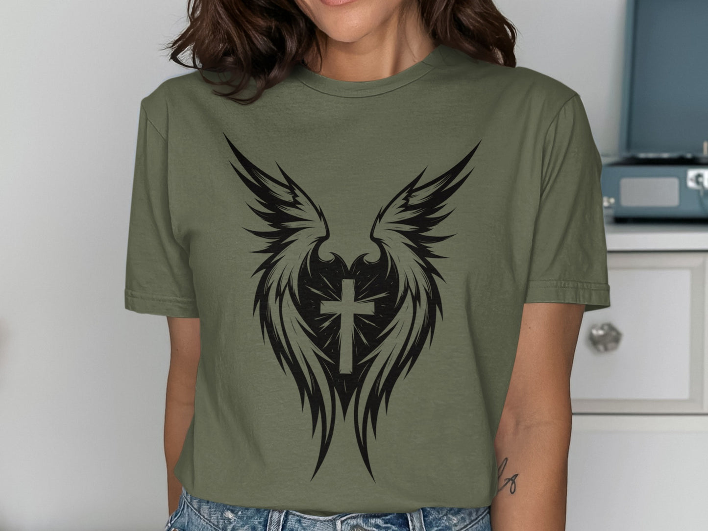 Green t-shirt with black winged cross graphic.