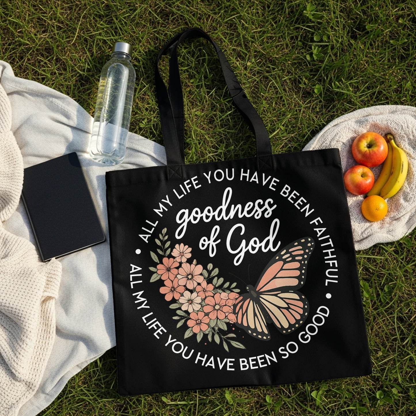 Black tote bag with floral and butterfly design, featuring "goodness of God" text.