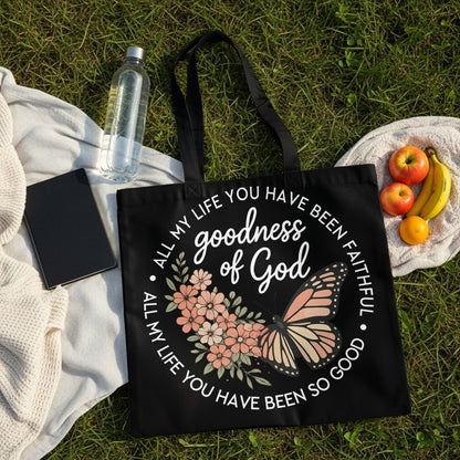 Black tote bag with floral and butterfly design, featuring "goodness of God" text.