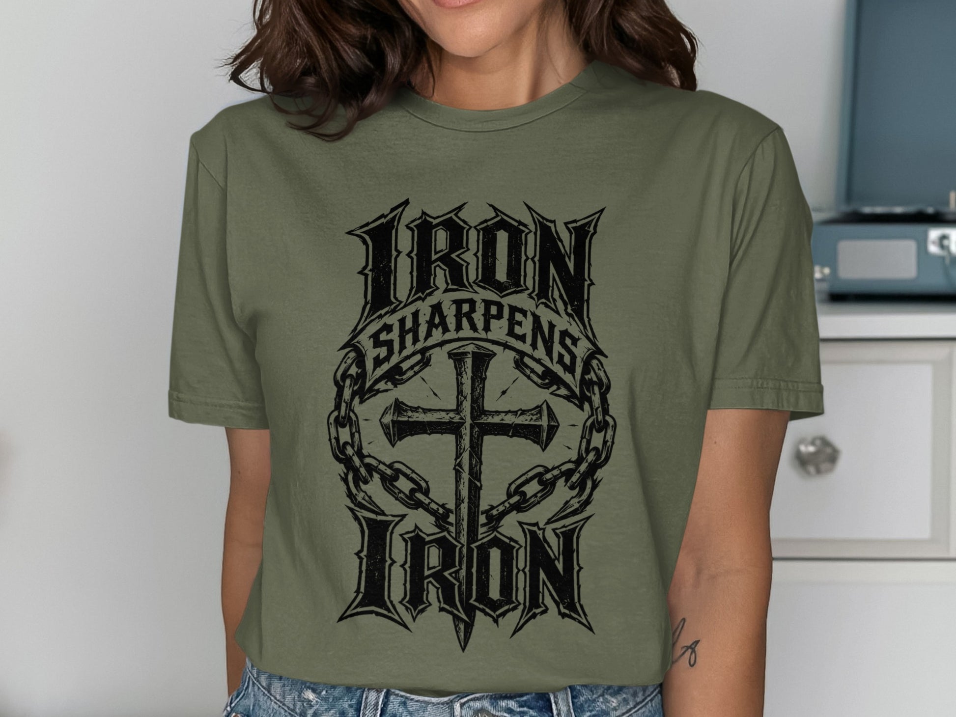 Olive green t-shirt with "Iron Sharpens Iron" text and a cross.