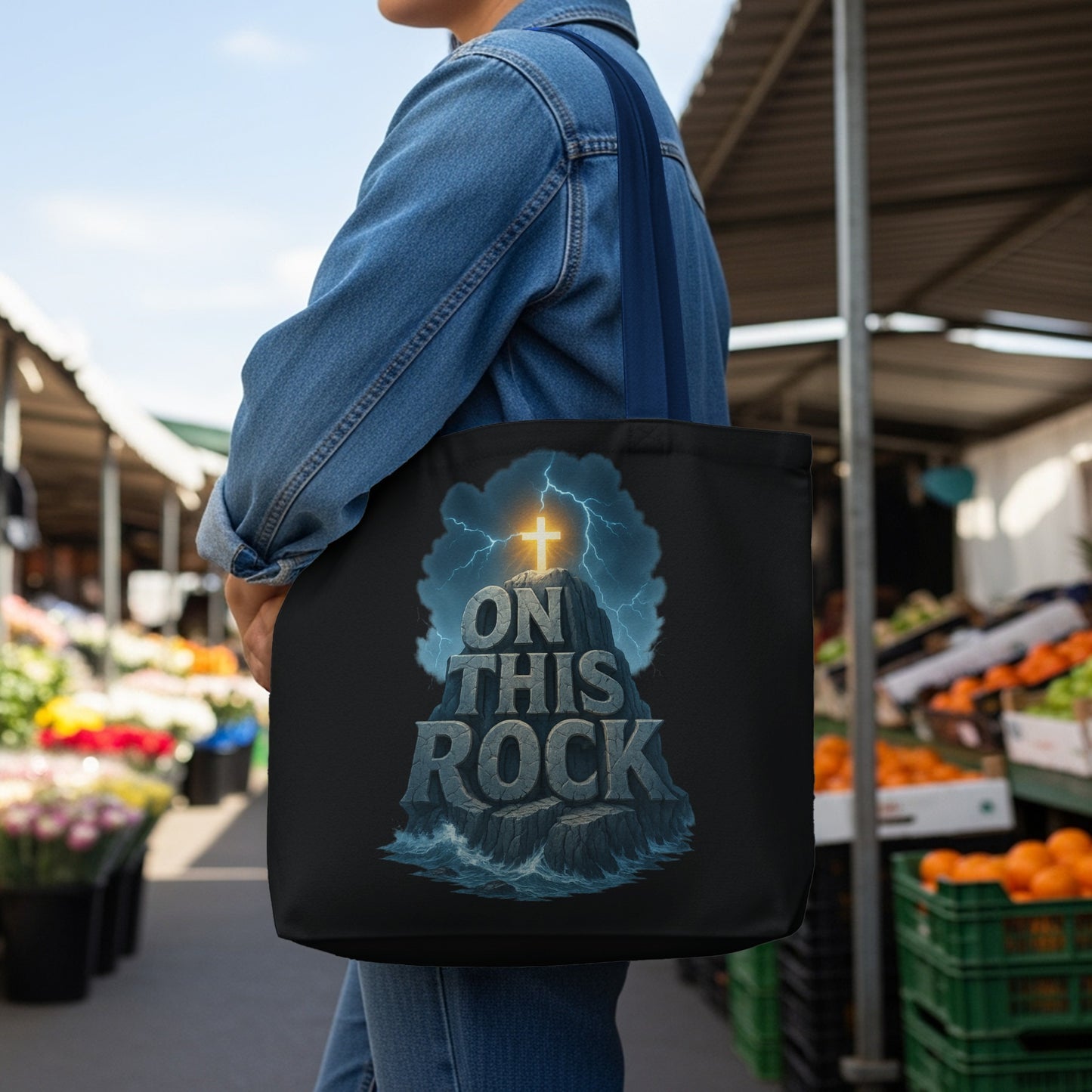 Black tote bag with "ON THIS ROCK" text and a cross atop a rocky outcrop.