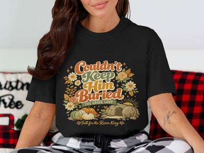 Black t-shirt with "Couldn't Keep Him Buried" graphic featuring pumpkins, flowers, and a tomb.