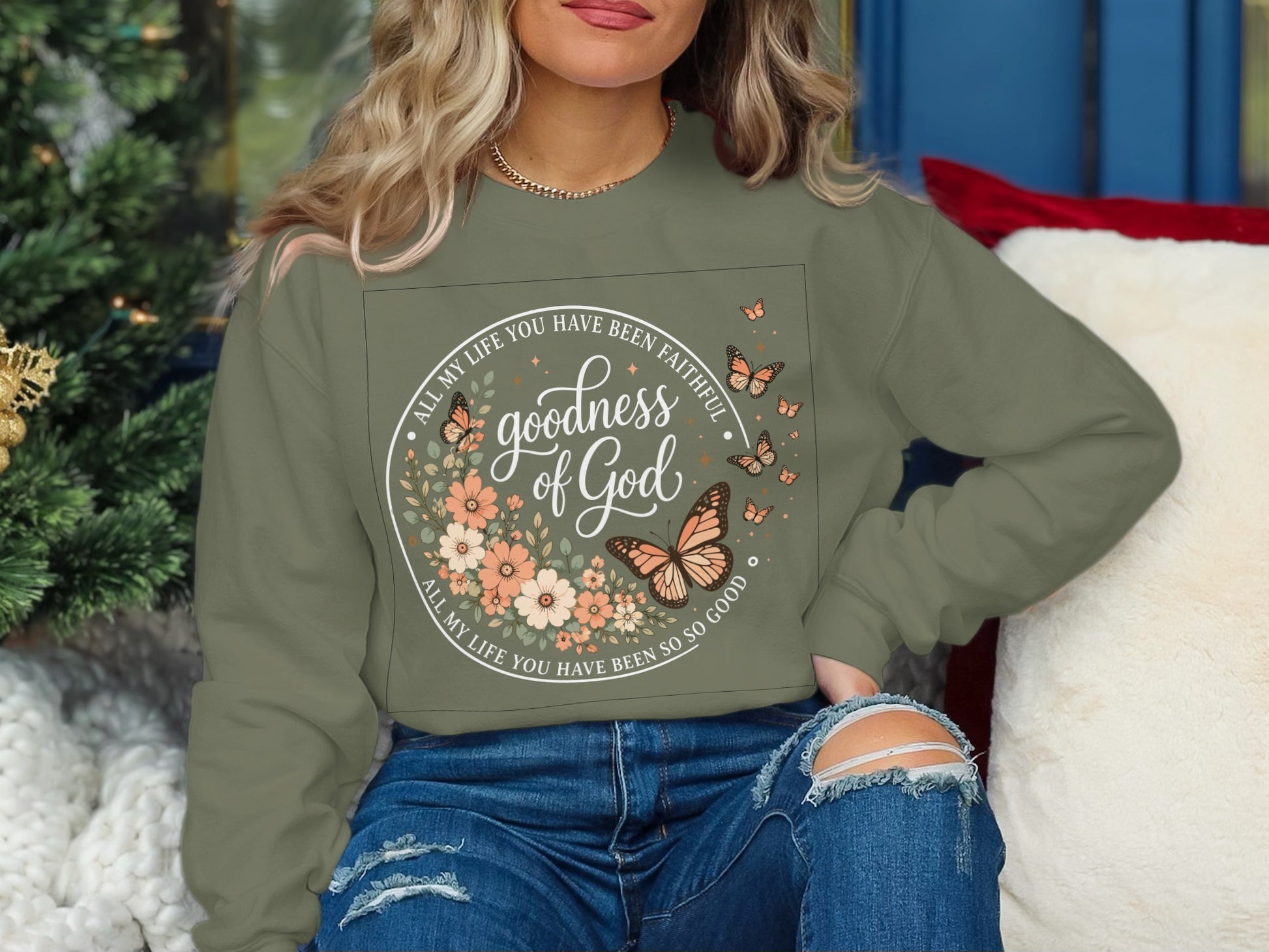 Green sweatshirt with floral wreath, butterflies, and "goodness of God" text.
