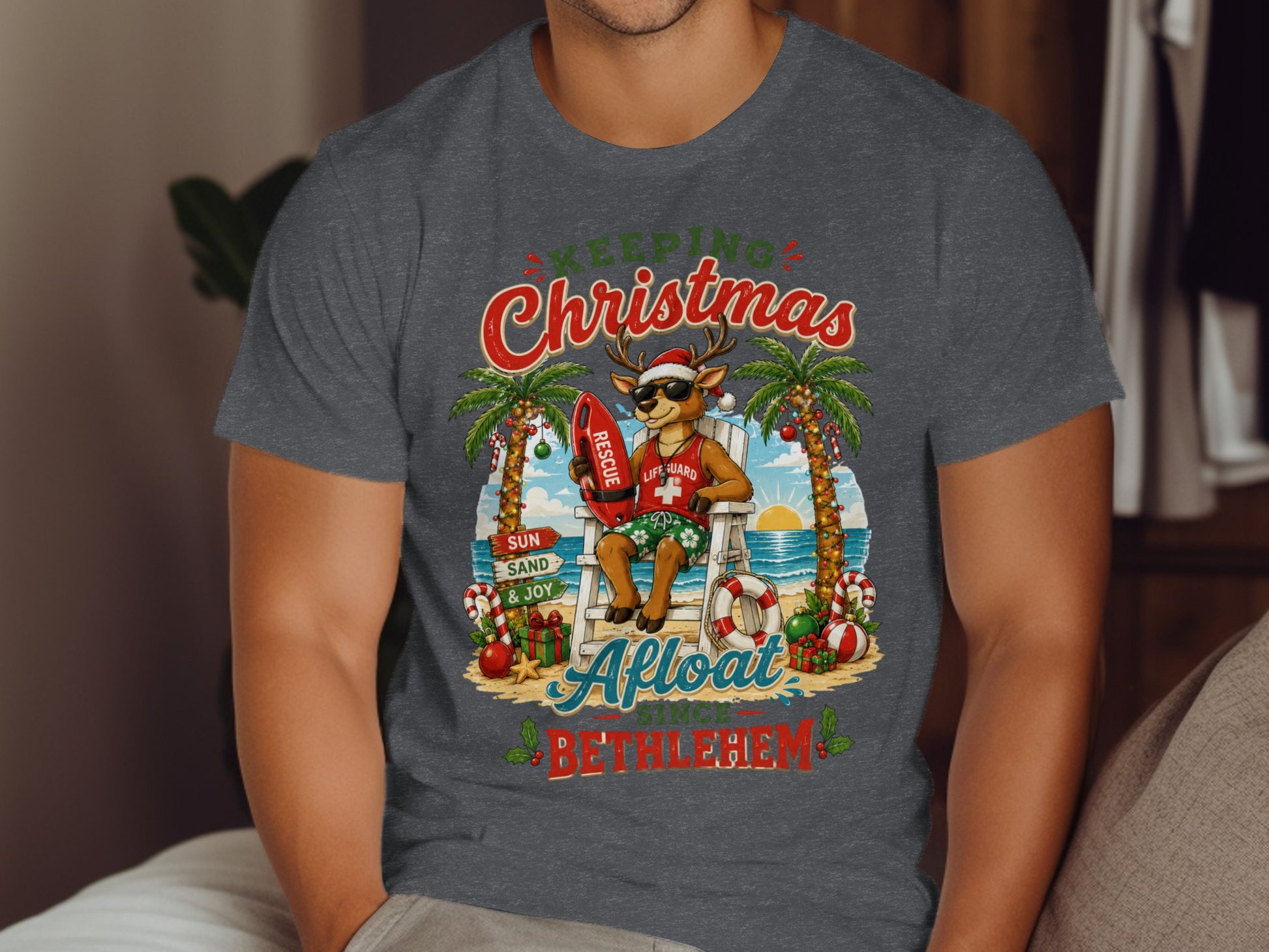 Deer lifeguard in Santa hat with surfboard on beach, text "Keeping Christmas Afloat Since Bethlehem".