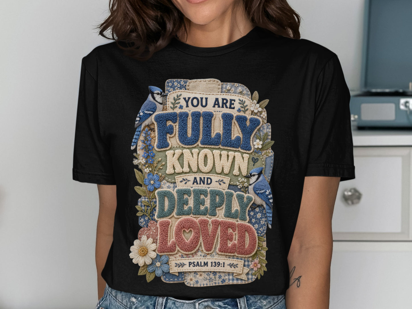 Black t-shirt with "You are fully known and deeply loved" text and blue birds.