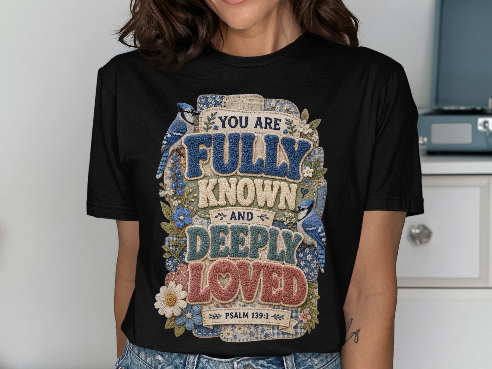 Black t-shirt with "You are fully known and deeply loved" text and blue birds.