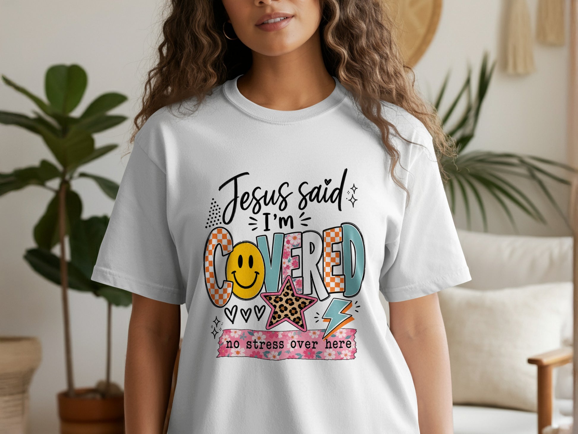 White t-shirt with "Jesus said I'm covered no stress over here" text and graphics.