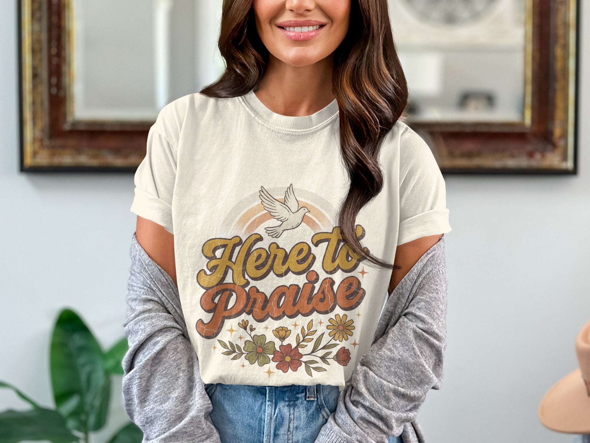 Cream t-shirt with "Here to Praise" text, a dove, rainbow, and floral graphic.