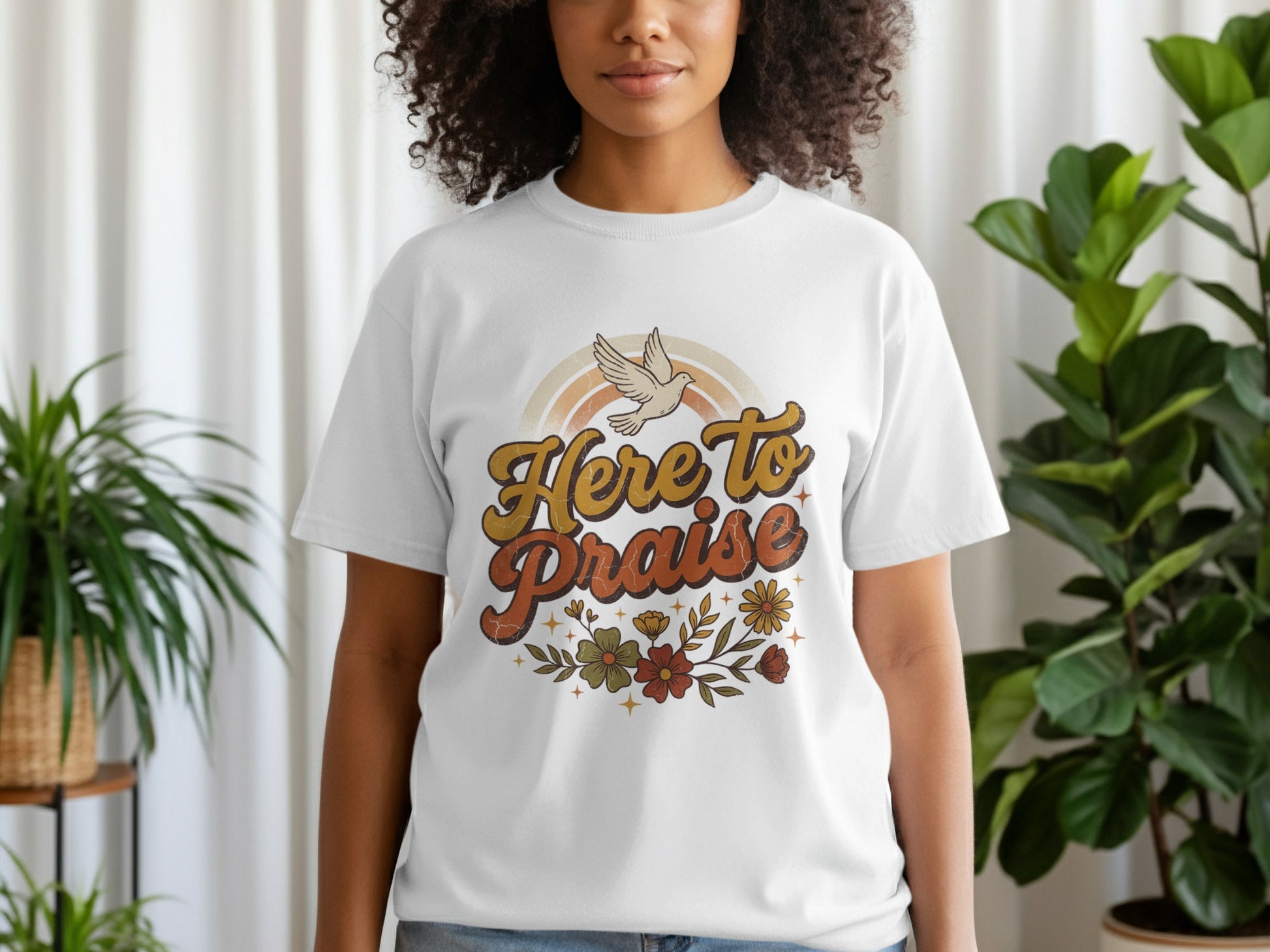 White t-shirt with "Here To Praise" text, dove, rainbow, and floral graphic.