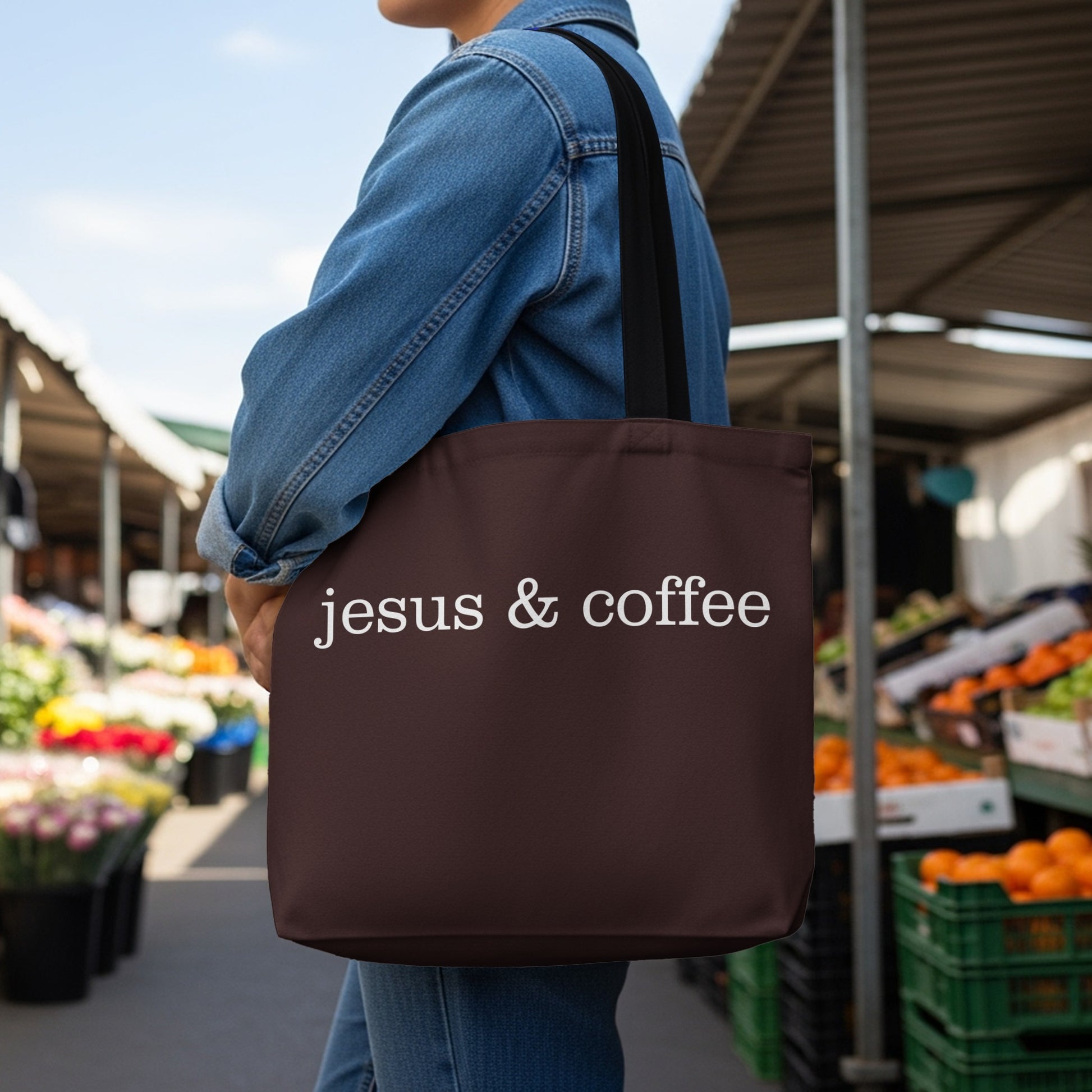 Brown tote bag with white text "jesus & coffee" worn by a person.