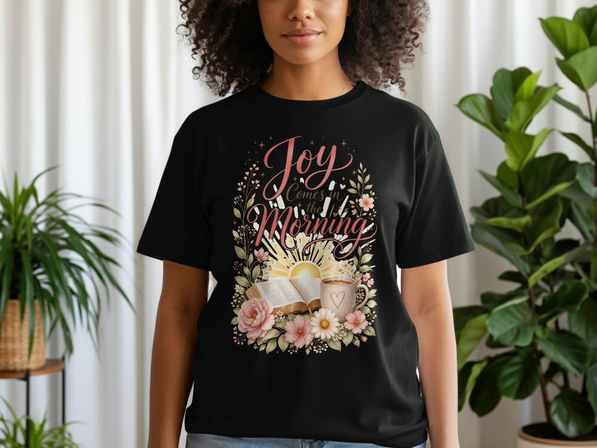 Black t-shirt with "Joy Comes in the Morning" text, Bible, coffee, and flowers.