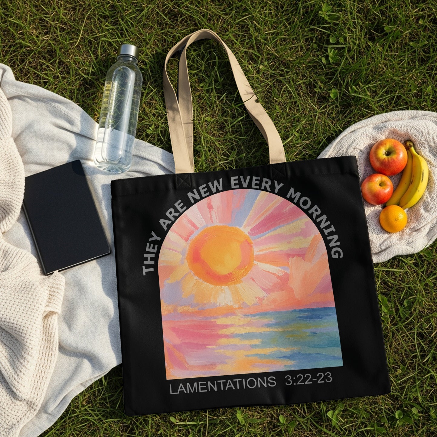 Black tote bag with sunrise over water and text: Lamentations 3:22-23