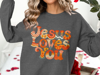 Dark gray sweatshirt with "Jesus Loves You" in colorful retro lettering.