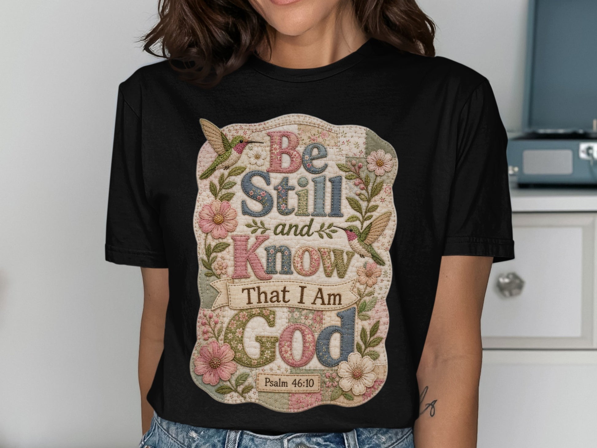 Black t-shirt with "Be Still and Know That I Am God" and floral designs.